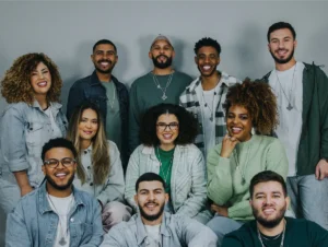 Grupo de pessoas sorridente em pose descontraída, representando diversidade e união, cada um vestido com roupas casuais e estilosos. A imagem transmite uma sensação de alegria e camaradagem.