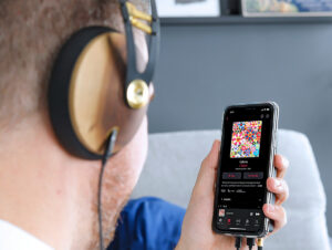 Tendências em música - Homem escutando música em seu celular com fones de ouvido, Luminate, relatório