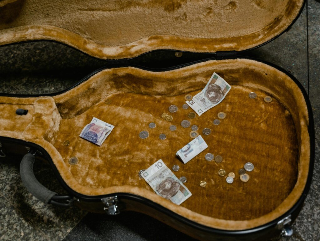 Informalidade no setor musical - Caixa de guitarra com moedas e notas de dinheiro